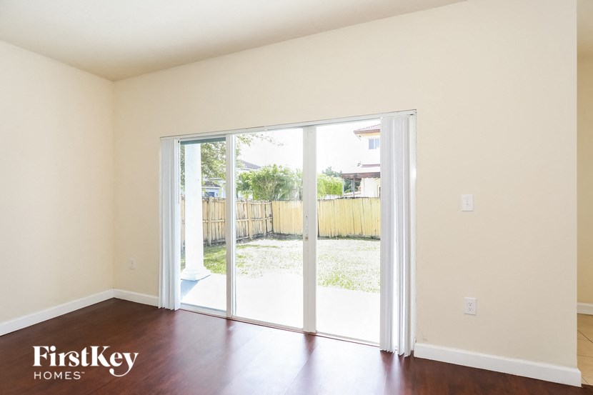 an empty living room with sliding glass doors to a backyard