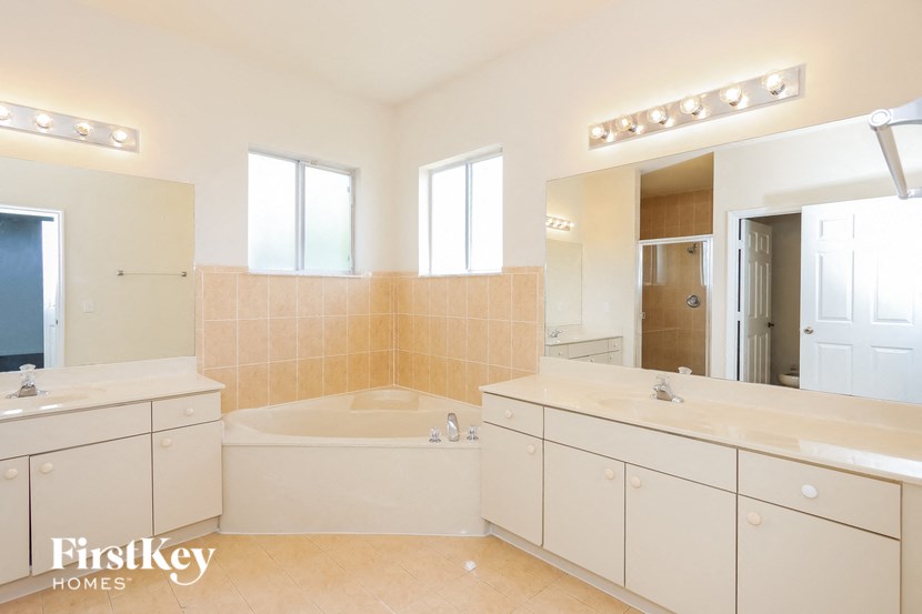a bathroom with two sinks and a tub and a large mirror
