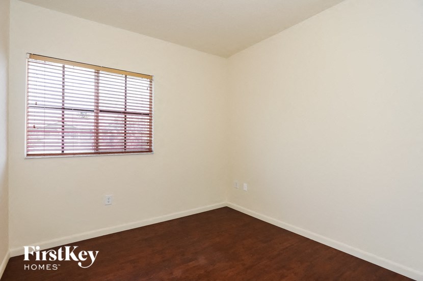 a bedroom with white walls and a window and wooden floors