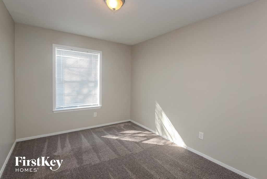 A room with a carpeted floor, a window, and a light fixture.