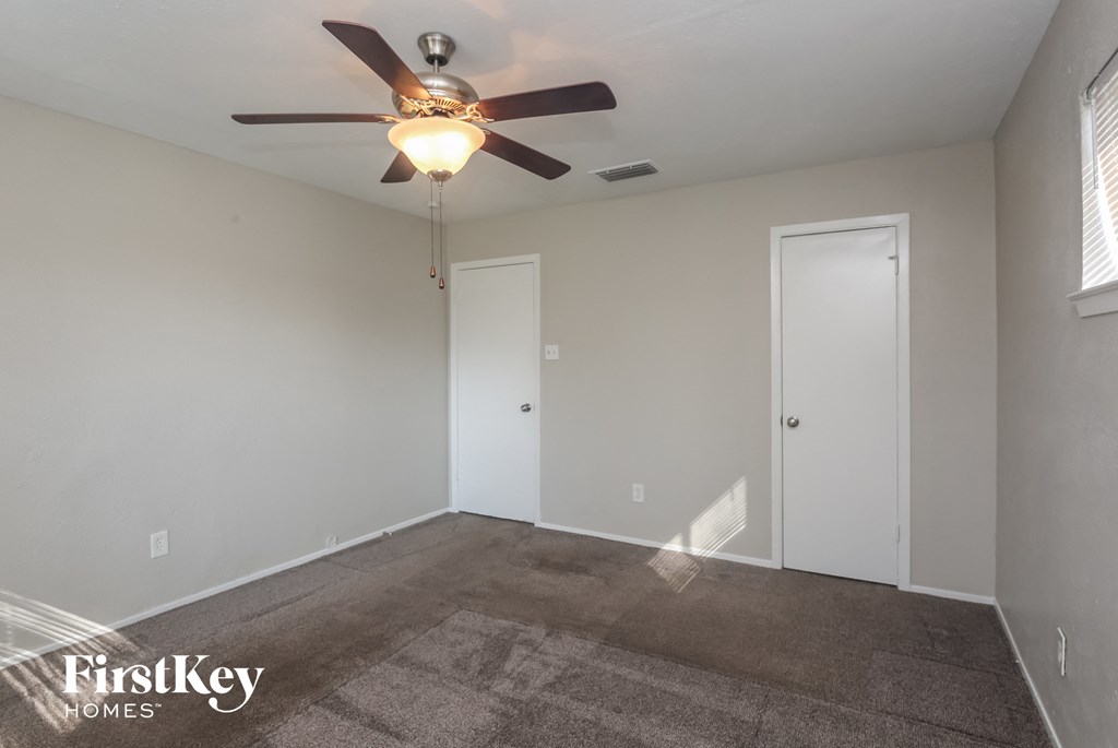 A room with a ceiling fan and two doors.