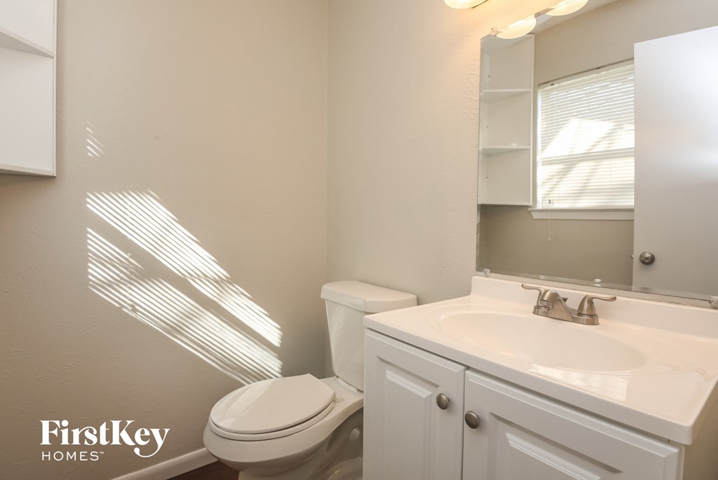 A white bathroom with a toilet, sink, and mirror.