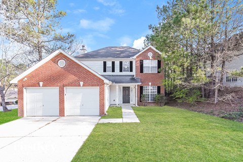 a brick house with two garage doors and a lawn