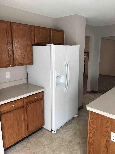 A white refrigerator in a kitchen with wooden cabinets.