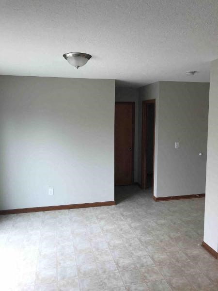 A room with a light on the ceiling and a door on the right.