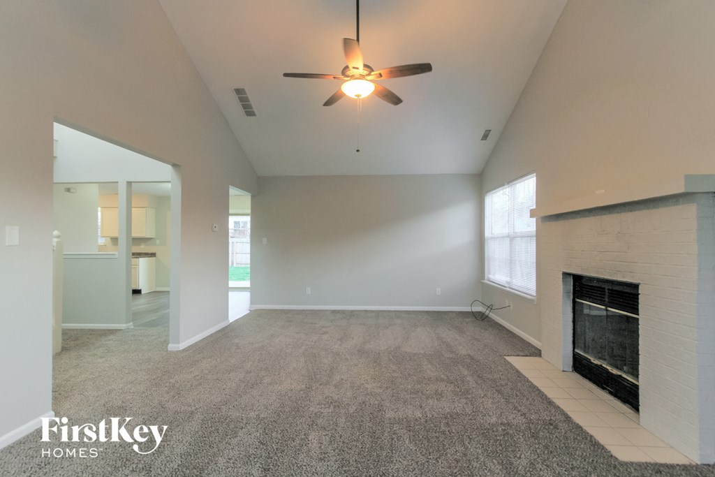 an empty living room with a fireplace and a ceiling fan
