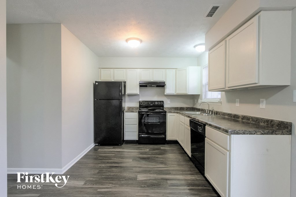 a kitchen with white cabinets and a black stove and refrigerator