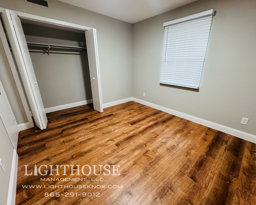A room with wooden flooring and a window with blinds.