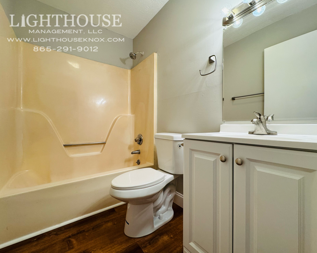 A white toilet in a bathroom with a wooden floor.