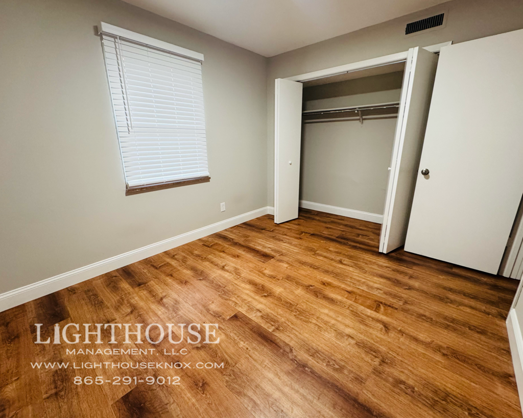 A room with wooden flooring and a white door is shown.
