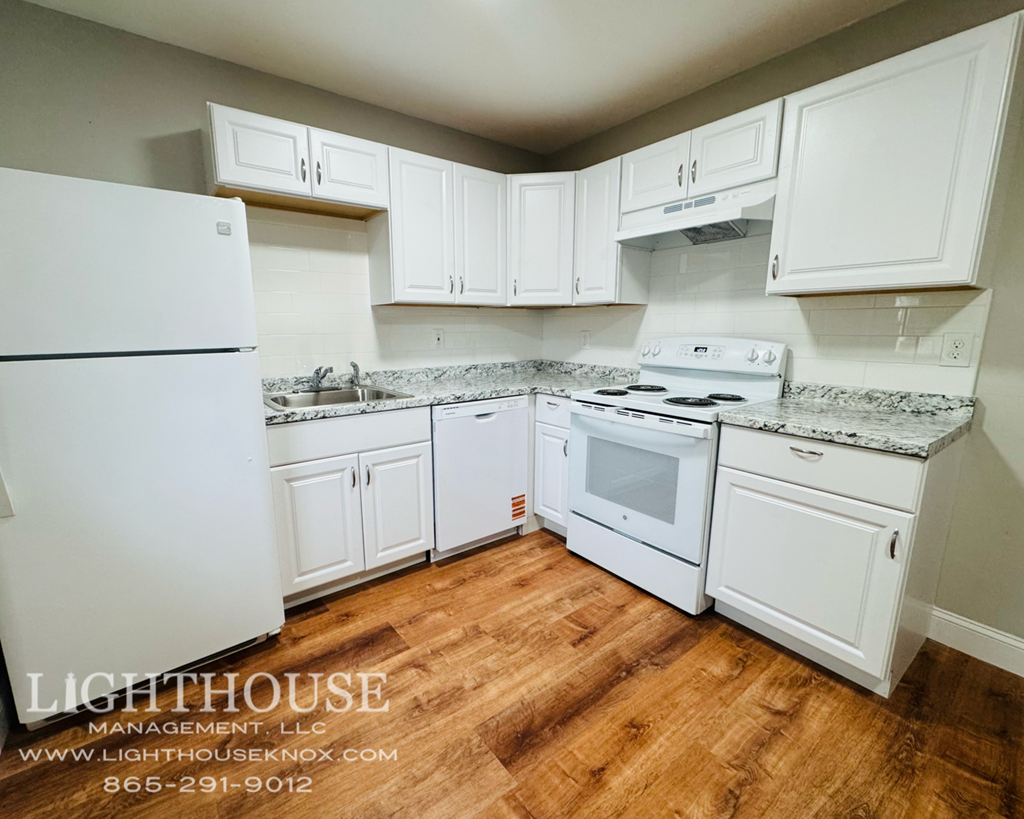 A white kitchen with wooden floors and a Lighthouse Management logo.