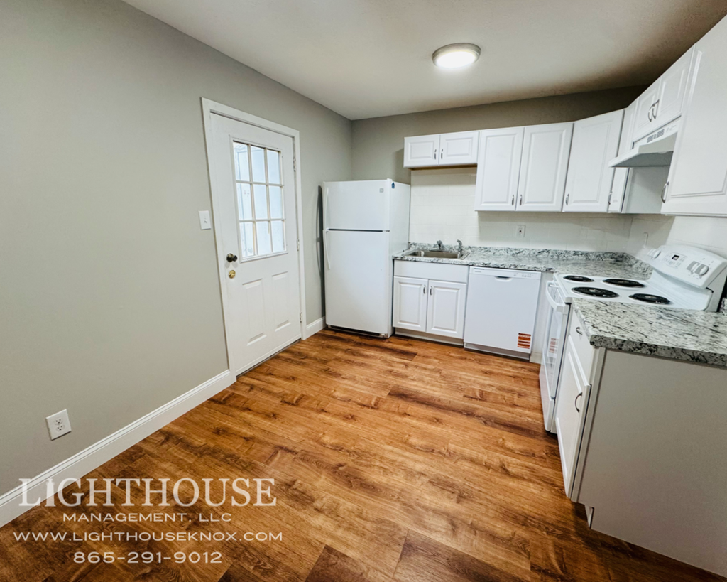 A kitchen with white appliances and wooden floors.