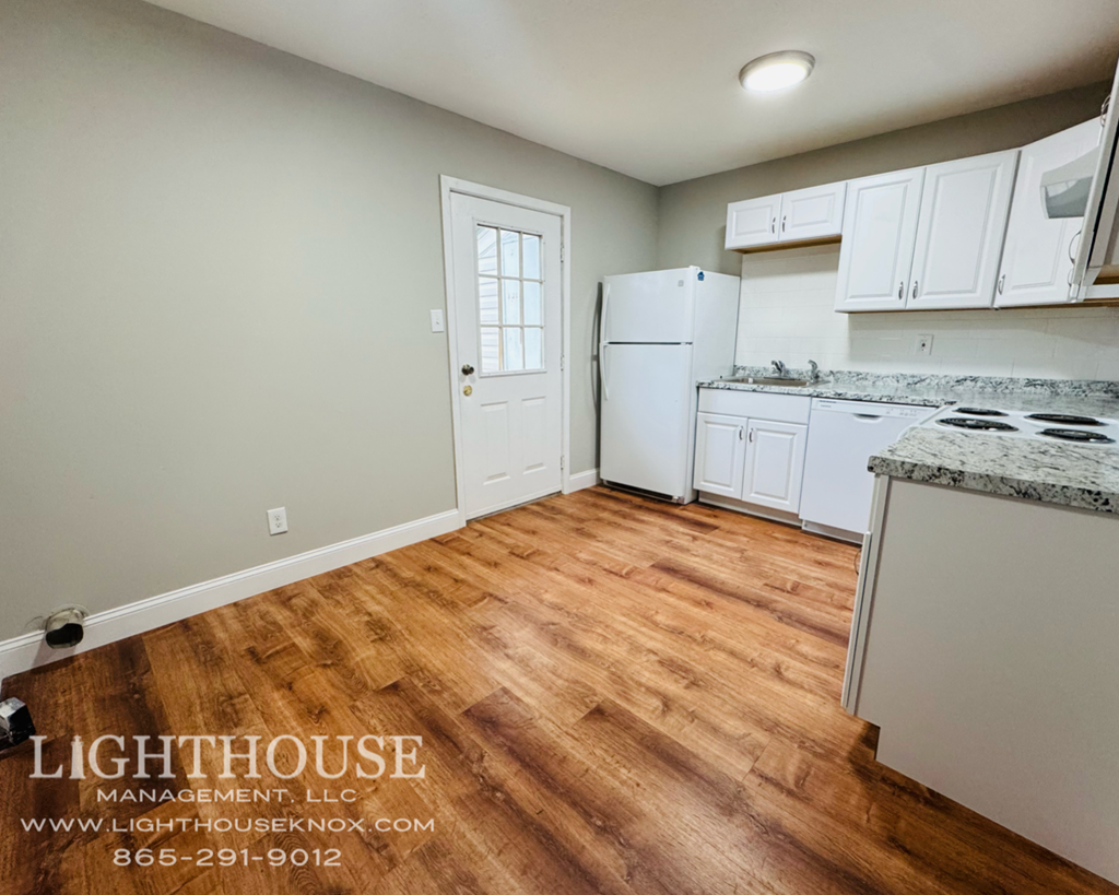 A kitchen with white cabinets and a wooden floor.