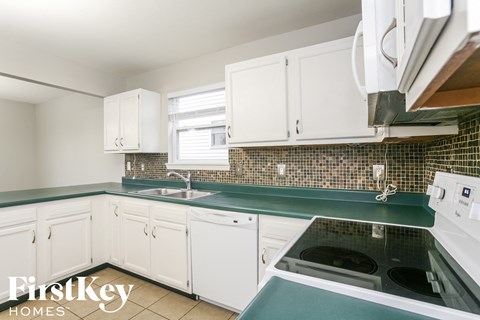 A kitchen with white cabinets and a green countertop.