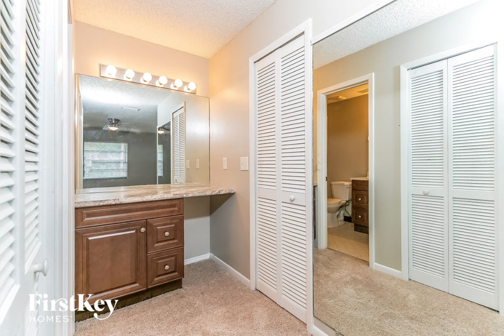 A bedroom with a vanity and a mirror.
