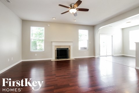 A spacious living room with a fireplace and a ceiling fan.