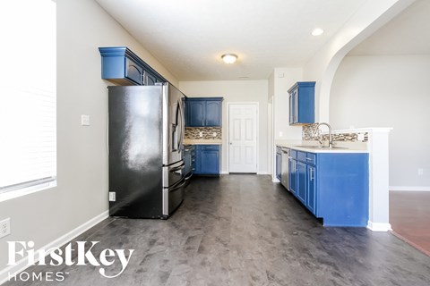 A kitchen with a black fridge and blue cabinets.