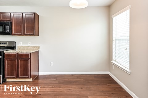 a kitchen with wood flooring and a window and wooden cabinets