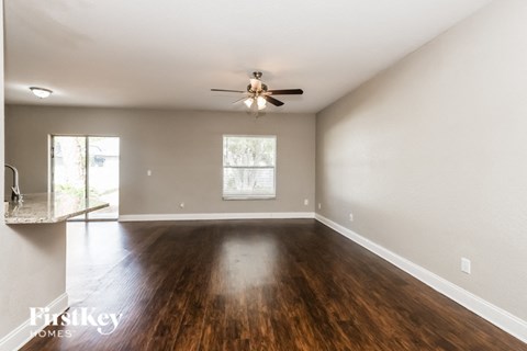 A spacious room with a ceiling fan and wooden flooring.