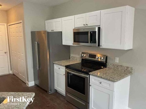 A kitchen with white cabinets and a stainless steel refrigerator.