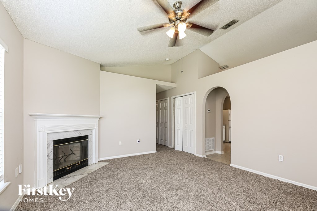 A spacious living room with a fireplace and a ceiling fan.