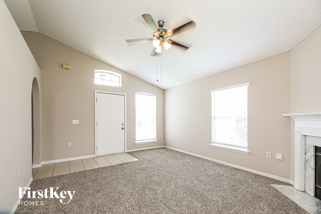 A spacious room with a fireplace and a ceiling fan.