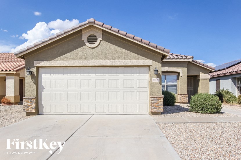 A house with a garage door in the foreground and a clear blue sky above.