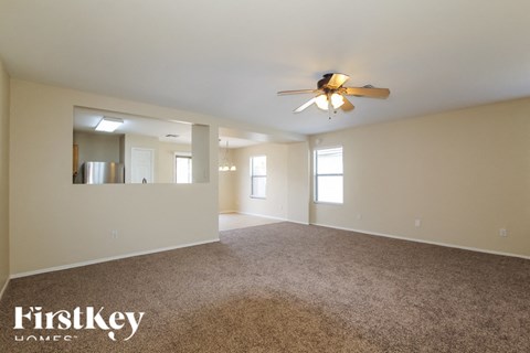 A spacious room with a ceiling fan and carpeted floor.