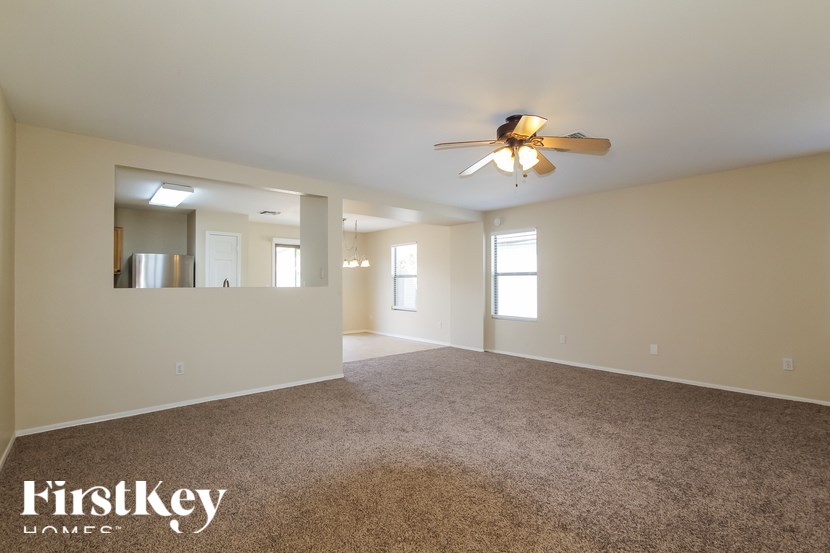 A spacious room with a ceiling fan and carpeted floor.