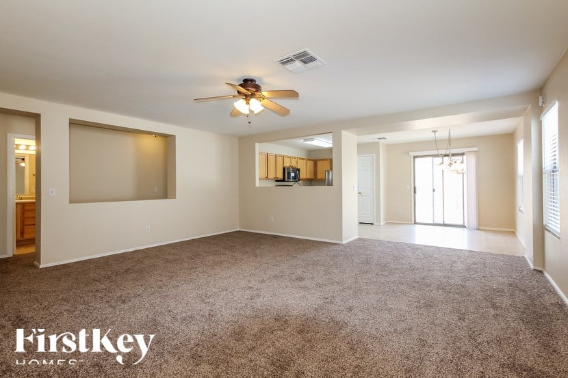 A spacious room with a carpeted floor and a ceiling fan.