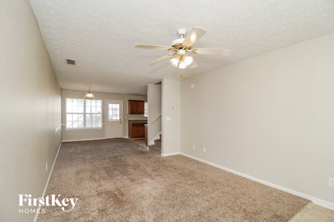 a spacious living room with carpet and a ceiling fan