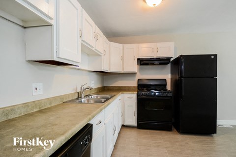 a kitchen with white cabinets and black appliances