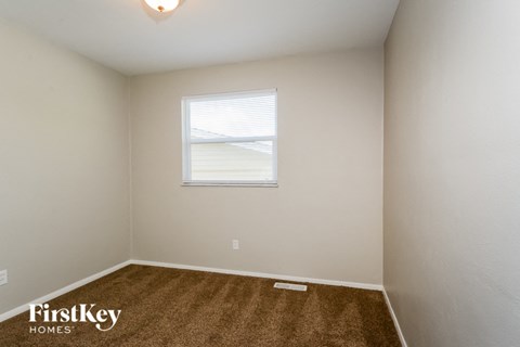 the living room of a small white house with a window and carpet
