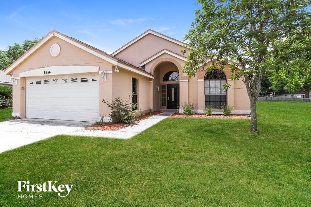 a beige house with a garage and a lawn