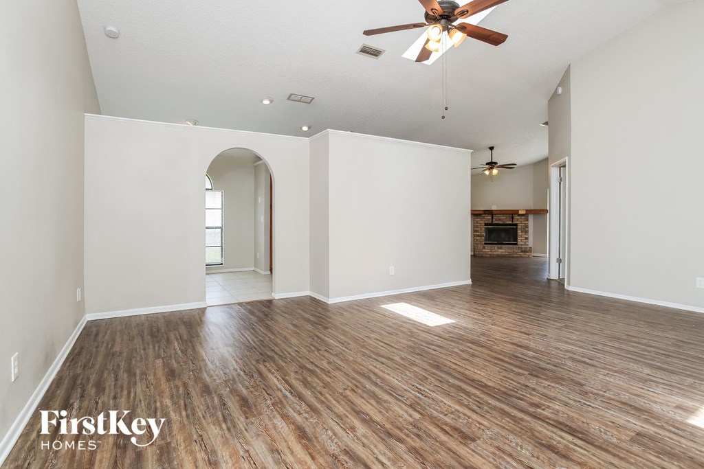 the living room and dining room with hardwood floors and a ceiling fan