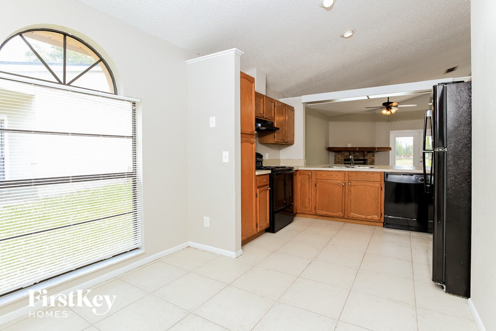 a kitchen with black appliances and wooden cabinets and a window