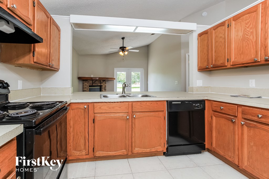 a kitchen with wooden cabinets and black appliances and a sink