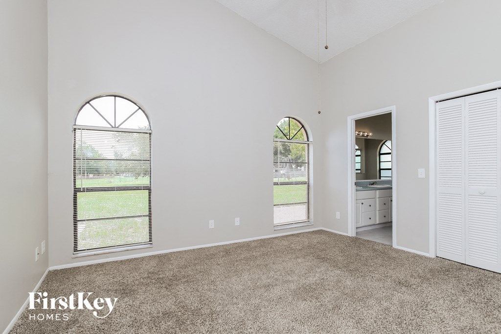 the living room of an empty house with carpet and two windows