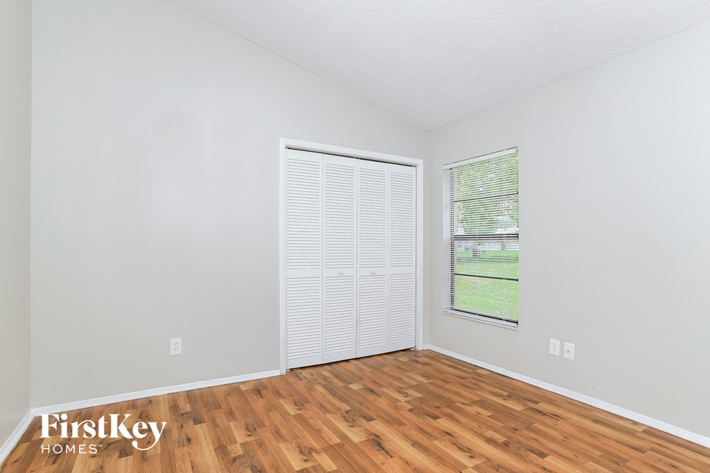 the living room of an apartment with wood flooring and a window