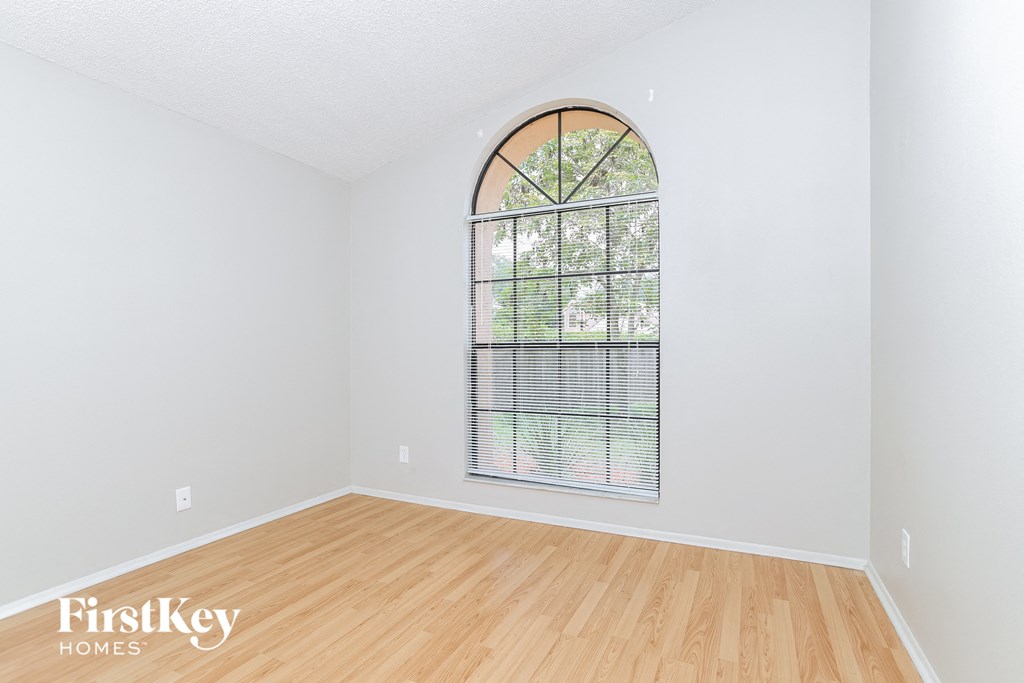 the living room of an empty house with a large window and wooden floors