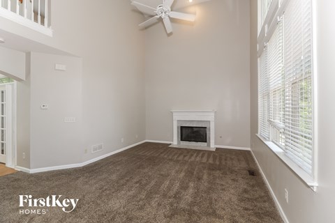 A spacious living room with a fireplace and a ceiling fan.