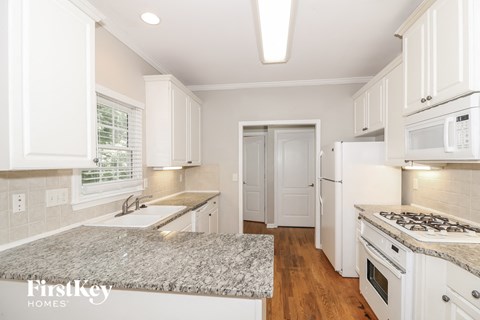 A kitchen with white cabinets and appliances.
