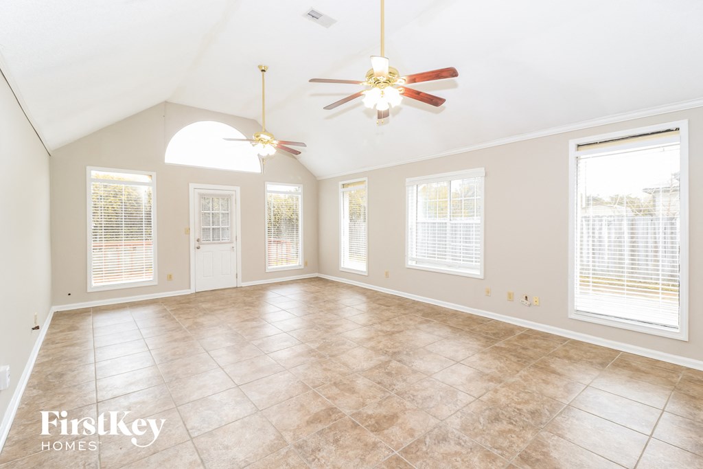 an empty living room with a ceiling fan and windows