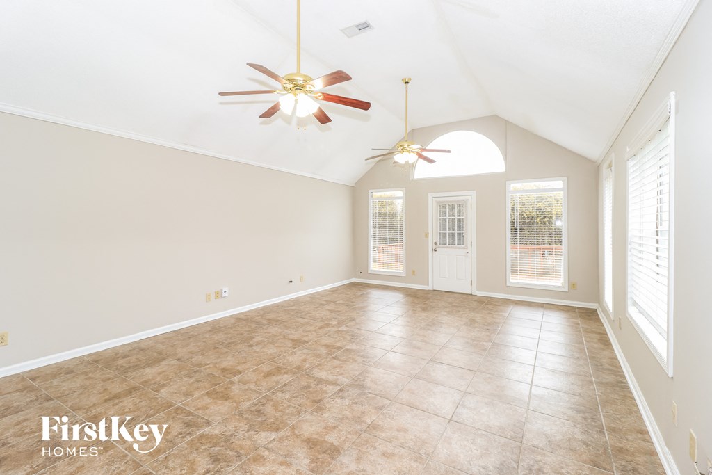 a clean and empty living room with two ceiling fans