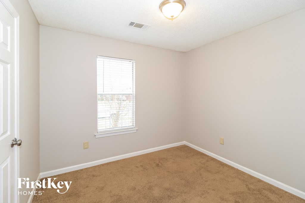 a bedroom with a carpeted floor and a window