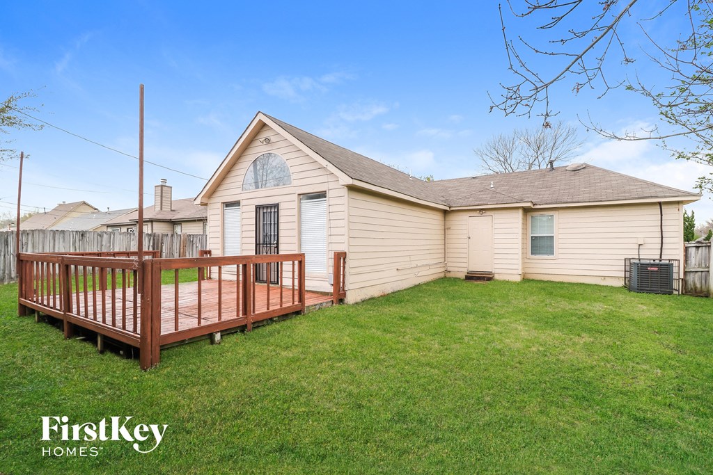 a backyard with a wooden deck and a white house