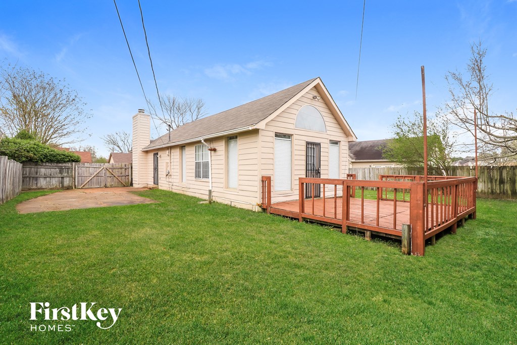 a backyard with a wooden deck and a small white house