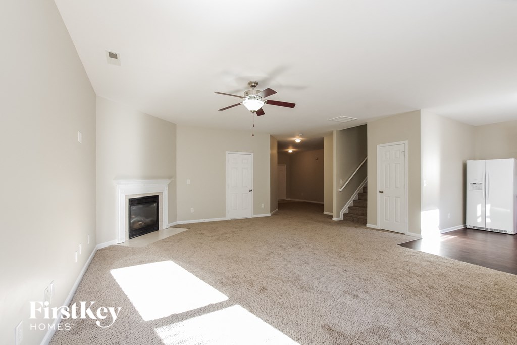 an empty living room with a ceiling fan and a fireplace