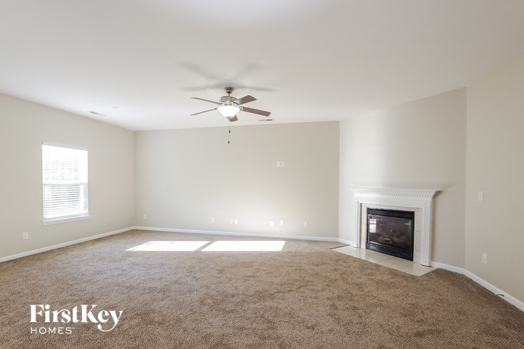 a empty living room with a ceiling fan and a fireplace