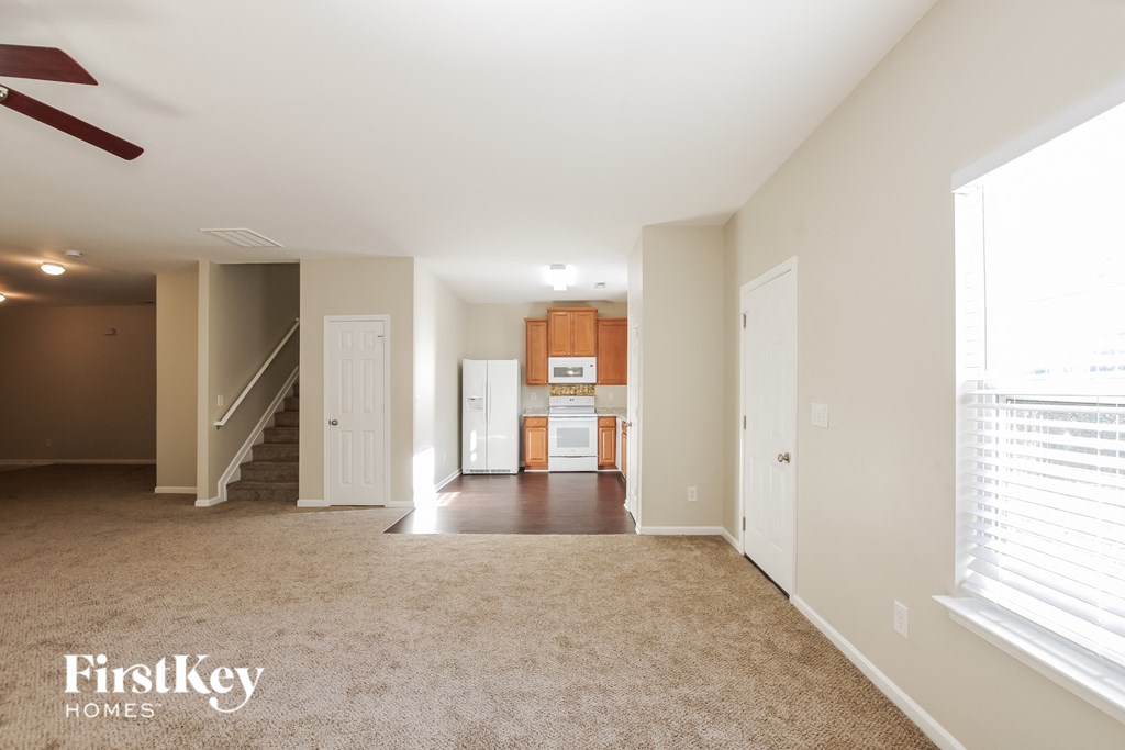 an empty living room with a kitchen in the background